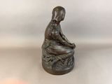 a statue of a woman sitting on a rock with a flower in her hand