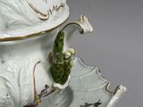 a white bowl with a lid and a green leaf on it