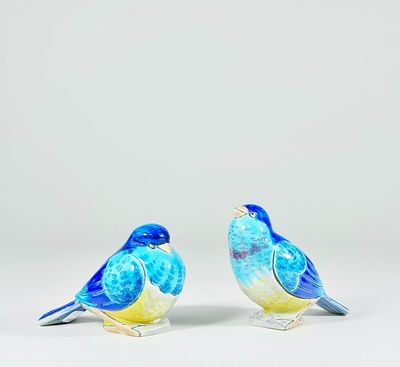 une paire de figurines d'oiseaux bleues et jaunes posées sur une surface blanche
