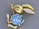 une image représentant une broche en forme de lapin avec une pierre bleue dans la gueule