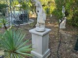 une statue représentant un homme debout sur un socle dans un jardin