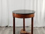 une table ronde au plateau en marbre noir trône sur un parquet