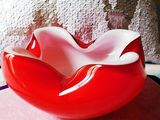 a red and white bowl sitting on top of a pillow