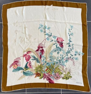 an image of a square scarf with flowers on it on a tiled floor