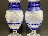 une paire de vases en verre bleu posés sur une table, sur fond gris