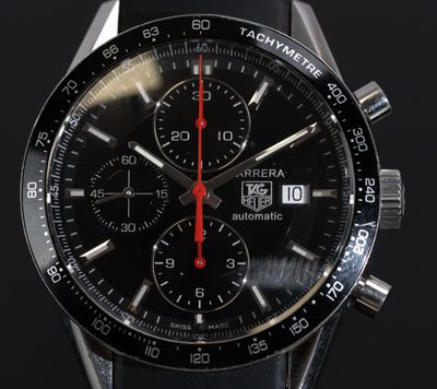 une montre noire avec une trotteuse rouge sur fond noir
