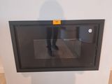 une personne debout devant un micro-ondes fixé au mur