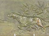 bronze plaque depicting a dog and a duck in a pond