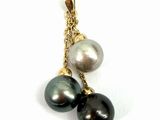 un gros plan d'un pendentif en perle noire et blanche monté sur une chaîne en or