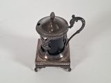 an antique silver plated teapot with a black cup on a stand