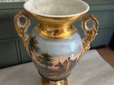 a vase with a painting on it sitting on a table