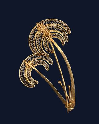 a gold plated broochle with a stylized design