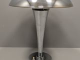 une photo d'une lampe de table argentée posée sur une surface blanche