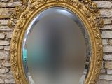un miroir au cadre doré ouvragé accroché à un mur de pierre, avec un mur de pierre en arrière-plan