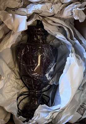 un vase marron posé dans une boîte avec du papier blanc