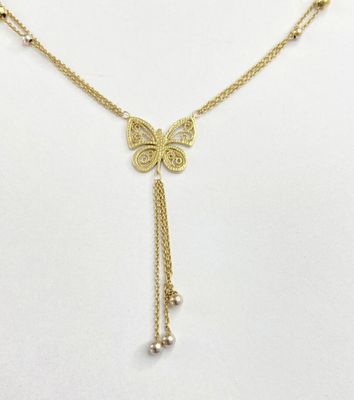 un collier représentant un papillon doré orné de perles sur fond blanc