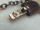 a small metal object on a chain on a white surface