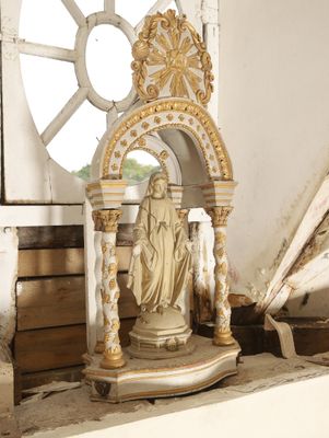 une statue représentant une femme, posée sur un socle devant une fenêtre