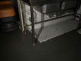a sink in the corner of a room with a metal counter
