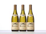 three bottles of white wine sitting on top of a table