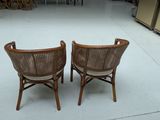 pair of wicker chairs in a store with a counter and chairs in the background