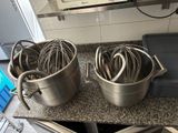 two pots with whisks in them sitting on a counter