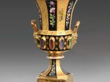 une image représentant un vase noir et doré orné de fleurs