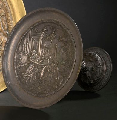 une assiette en or ornée d'une image, à côté d'une autre assiette en or ornée d'une image