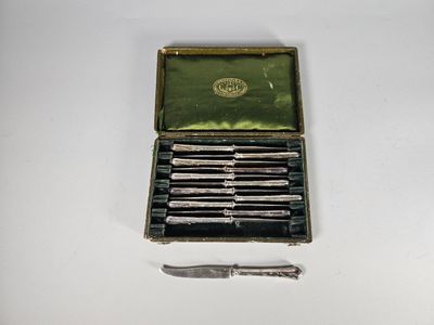 une petite boîte contenant six couteaux, posée sur une surface blanche