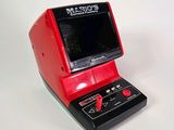 un appareil électronique rouge et noir posé sur une surface blanche