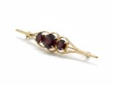 a close up of a gold brooch with three garnets on it
