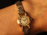 a woman ' s wrist with a gold watch on it