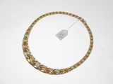 une photo d'un collier en or posé sur une table blanche