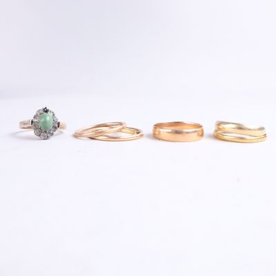 three gold rings and a green stone ring on a white background