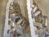 silver and gold sandals with white soles on a wooden floor