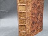 an old book sitting on top of a table covered in books
