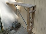 a wooden table with a shelf on it in front of a building