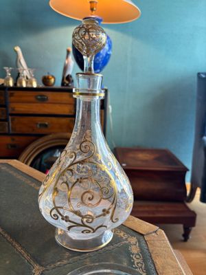 une bouteille en verre posée sur une table, sur laquelle est posée une lampe