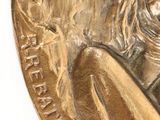 a gold medal with a woman holding a sword