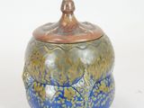 a blue and gold jar with a lid on a white surface
