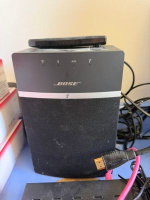 une enceinte noire posée sur un bureau, à côté d'un chargeur