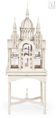 a white bird cage with a building on top of it