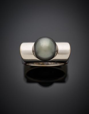 un gros plan d'une bague ornée d'une perle sur un fond noir