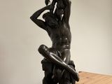 statue of a man sitting on a bench with a sword in his hand