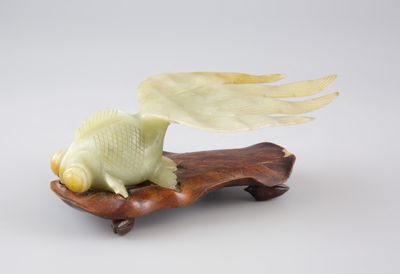 figurine sculptée représentant un poisson ailé, posée sur un socle en bois
