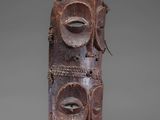 a close up of a wooden mask on a grey background