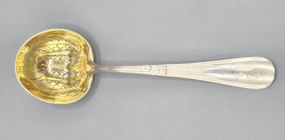 an antique silver spoon with a gold handle on a gray surface