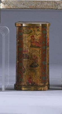 a small metal container with a gold design on it