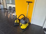 un aspirateur jaune et noir posé par terre à côté d'une chaise