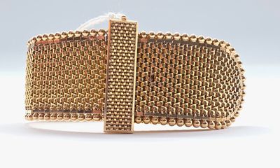 a close up of a gold bracelet on a white surface
